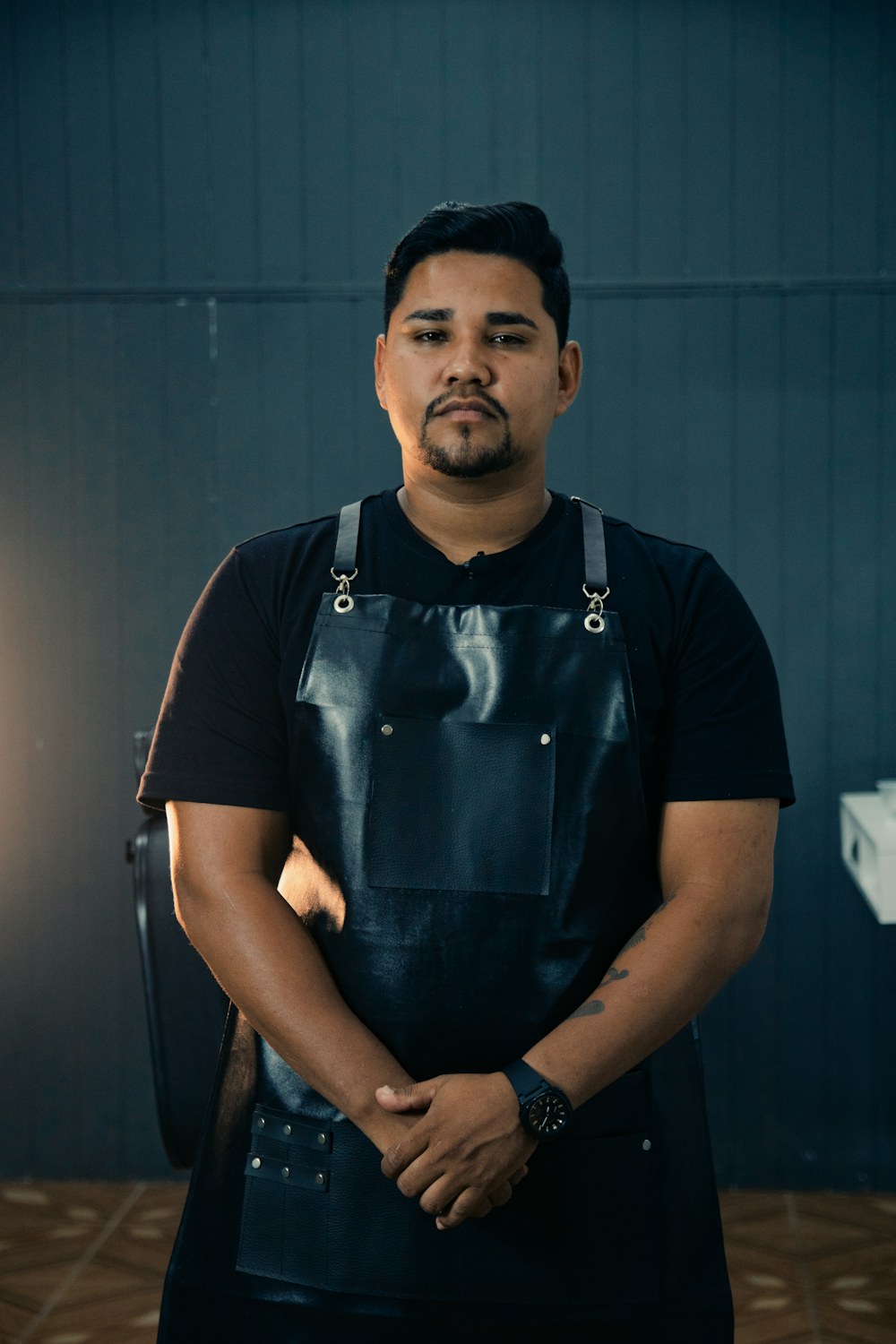 Fictional barber in a dark apron, posed for a staff portrait