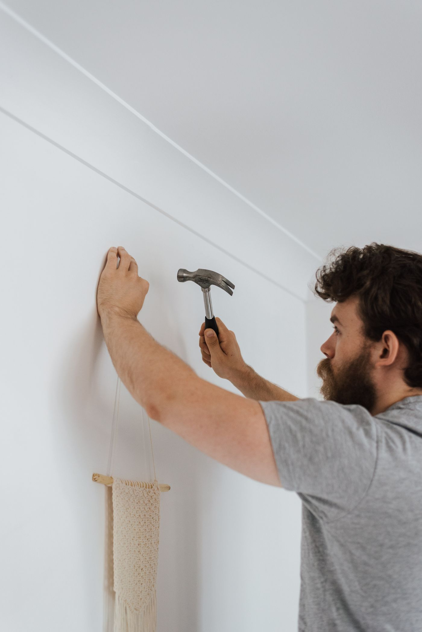 Handyman carefully hanging a wall accent in a bright home interior